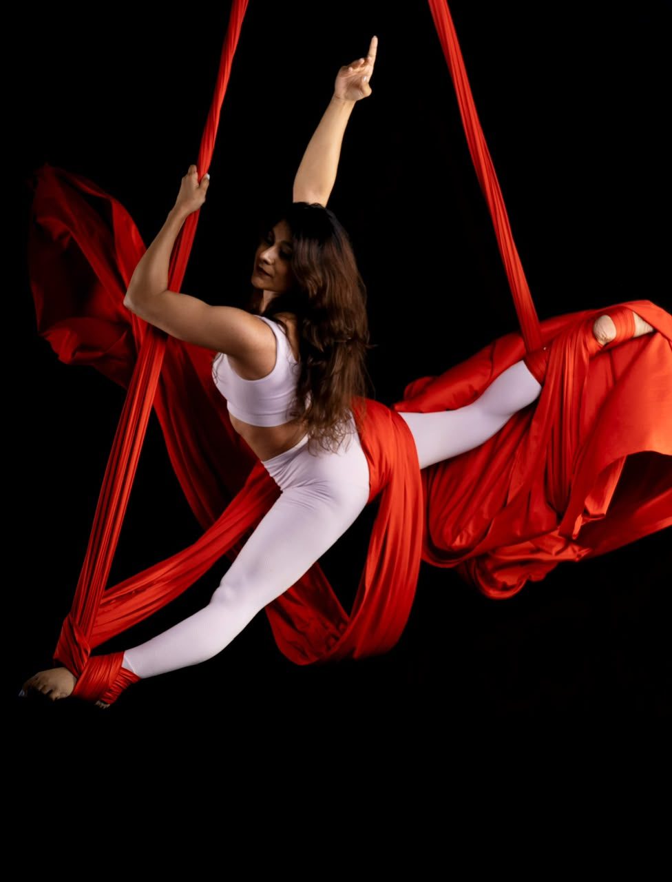 Roshani Tarapore performing a split on red aerial silks